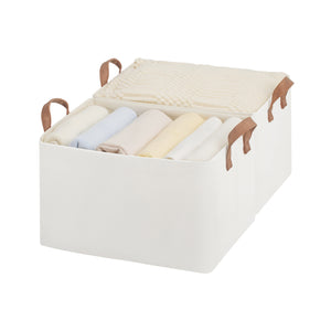 White storage bin with brown handles containing folded clothes on a white background
