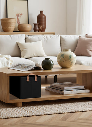 Living room with a white sofa, wooden coffee table, and decorative items. A black storage bin in the wooden coffee table.