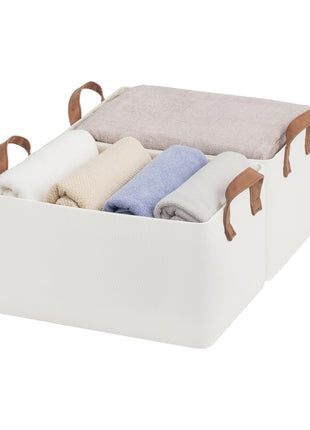 Storage bin with handles containing folded clothes on a white background