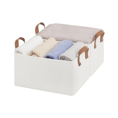 Storage bin with handles containing folded clothes on a white background